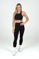 Front view of the Empower Crop in black, featuring a high neckline and supportive sustainable activewear design
