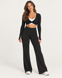 Women's black high-waisted wide leg leggings styled with a black twist crop top and white sneakers by HER Equilibrium Revived.