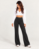 Women's black high-waisted wide leg leggings styled with a white zip up jacket and white sneakers by HER Equilibrium Revived.