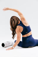 Woman in royal navy blue activewear stretching with racer back design
