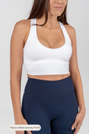 Woman wearing a white sports bra mid length and navy leggings for styled look